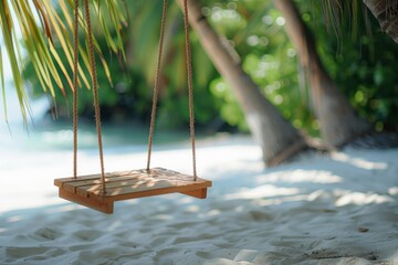 Wooden swing hanging from a palm tree above the soft white sand of the tropical beach.