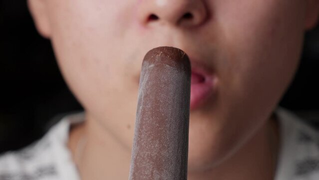 Chocolate frozen ice cream bitten by male caucasian mouth chewing closeup, cream flavor inside