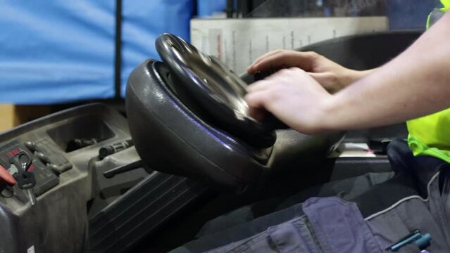 workers driving electric forklift inside a warehouse close up on skilled hand turn the steering wheel