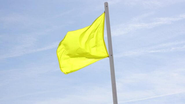 Yellow beach warning flag, on a windy day.