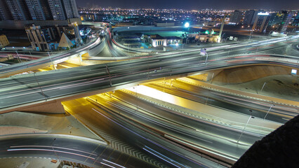 Traffic on a big road junction in Ajman aerial view from rooftop at night timelapse.