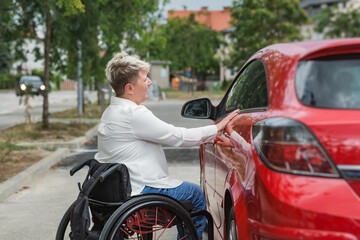 Female driver with disability entering a car, a wheelchair user on the way to work. Concepts of...