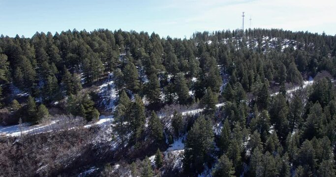 Aerial view flying up a New Mexico mountainside covered in snow with a cell tower