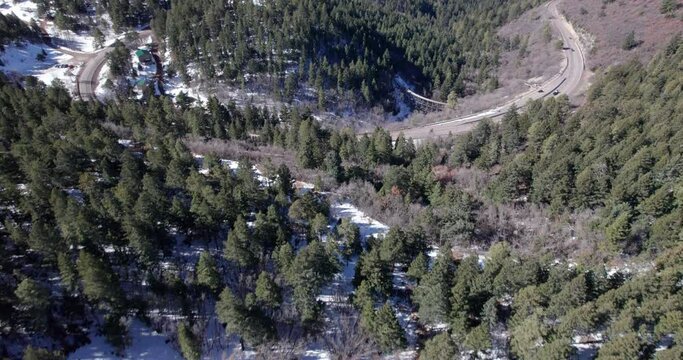 Aerial view flying over a rural mountain highway and snow covered valley
