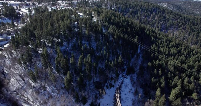 Aerial view flying over snowy New Mexico mountains with a historic narrow gauge railway truss