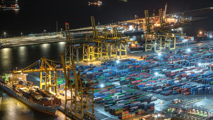 Seaport and loading docks at the port with cranes and multi-colored cargo containers night timelapse