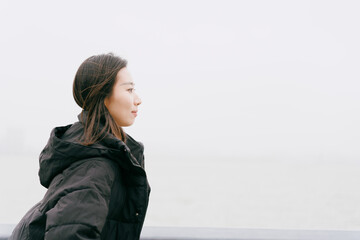 On cloudy winter days, Asian women walk along the seaside boardwalk