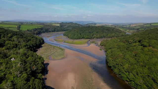 Aerial view of River Erme flowing through dense woods and green fields in south Devon, England, UK