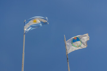 Flags of Argentina and Jujuy flying over a blue sky.
