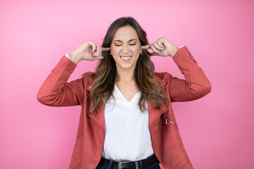 Young beautiful woman wearing casual jacket over isolated pink background covering ears with...