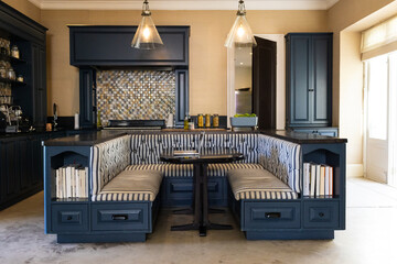 A modern kitchen with dark cabinets and cozy booth-style seating area
