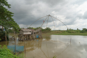 Fishing trap net in canal with fisherman urban city village town houses, lake or river. Nature...