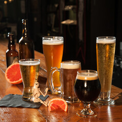 A variety of beers with citrus garnish on a dark wooden bar