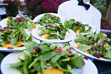 Waiter presenting plates of fresh garden salads at an event.