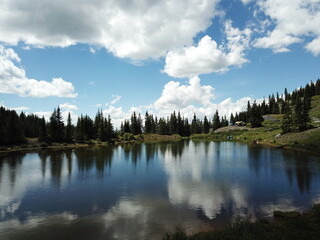 Fototapeta na wymiar Evergreen trees encircle a serene lake under a clear blue sky