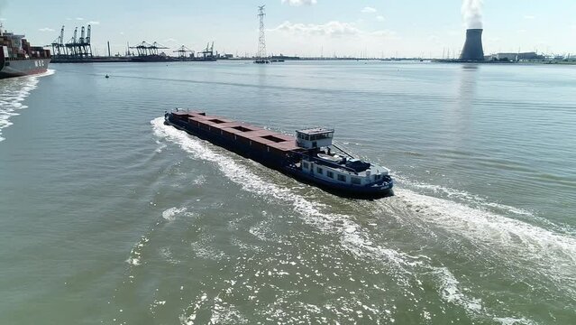Drone footage of a big barge entering the port of Antwerp on a sunny day, Belgium