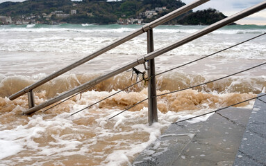Waves flooding the stairs to the beach in San Sebastian, Spain, during high tide
