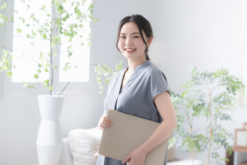 Beautiful woman with laptop in beautiful office window holding computer, smiling for camera, with...