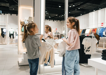 Two Young Girls Trying on Clothes at a Modern Fashion Retail Store