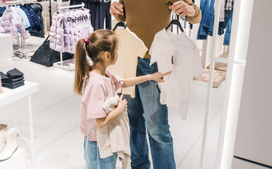Young Girl Shopping With Parent for Clothes in a Bright Retail Store
