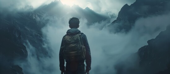 The back of a man with a bag on his back, standing on a high mountain, looking down,mysterious content,Dramatic light, generated with AI