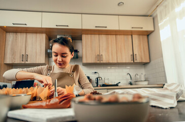 Culinary Craftsmanship: woman in sunlit kitchen, attentively engaged in pastry creation, with...