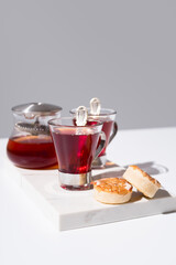 Dos tazas de té rojo con pasteles y dulces sobre mármol y fondo gris	