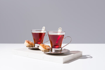 Dos tazas de té rojo con pasteles y dulces sobre mármol y fondo gris	