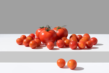 Surtido de tomates maduros sobre una mesa blanca y fondo gris - obrazy, fototapety, plakaty