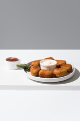 Plato de croquetas fritas con salsa de tomate y mayonesa aperitivo sobre fondo gris 