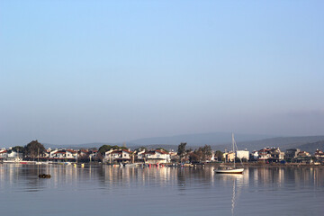 bay with a sailboat and houses on the horizon