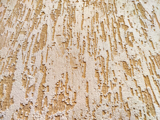 Peeling Beige Paint on a Rough Wall Texture. Weathered wall with flaking paint exhibiting aging