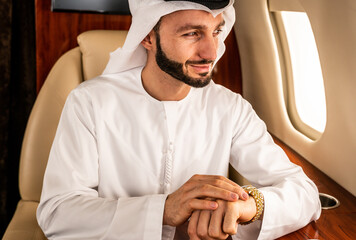 Arabian businessman wearing corporate business emirate kandora flying on luxury private jet,...