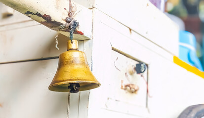 Low angle view of An antique and discolored broze ship's bell with rope lanyard hooked on a wooden cart.