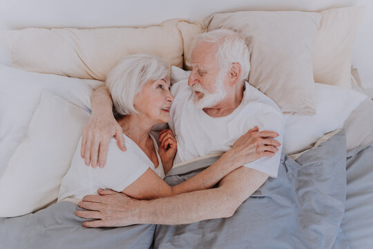 Elderly couple at home hugging in bed - Married senior couple portrait, concepts about old people lifestyle, quality of life and emotions - Powered by Adobe