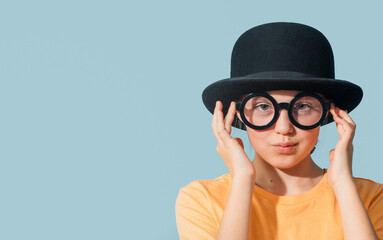 Fashionable looking teen girl in an old-fashioned bowler hat and round glasses. Banner on blue....