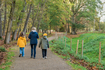 Family walk in the autumn park. Mom and two children on the trail in autumn