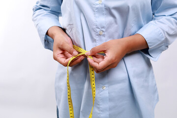 Close up woman in blue shirt measuring her waist with yellow measuring tape. Weight loss, slim body, healthy lifestyle concept. Figure control and counting calories. Successful diet plan.