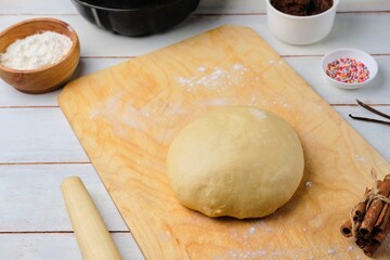 Step-by-step cooking of twisted yeast bread with poppy seed filling. Step one, prepared dough on a wooden board, poppy seed filling, sugar decorations.