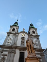 Fototapeta na wymiar Mariahilf Church and Josef Haydn Statue and Moon in the Sky at Mariahilfer Strasse in Vienna Austria