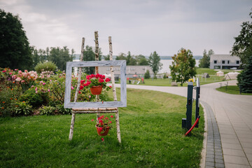 Dobele, Latvia - Augist 18, 2023 - Rustic wooden easel holding a hanging flower pot, in a garden...