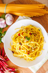 A plate of spaghetti aglio e olio with chili flakes, fresh parsley, garlic, and a drizzle of extra...