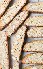 almond biscotti on white parchment lined tray, almond cantucci cookies on a white board, flatlay of slices of biscotti cookies or twice baked cookies