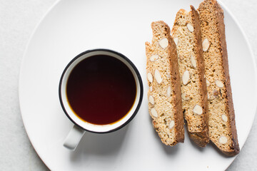 overhead view of coffee and almond biscotti on a white background, almond cantucci cookies on a...