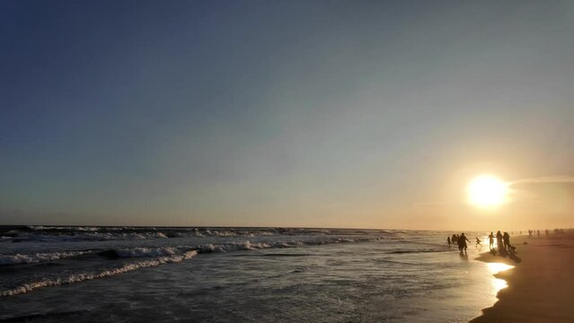 Indonesian people are enjoying sunset on depok beach during sunny day with cliffs rocks backgrounds at Parangtritis Beach, Bantul, Jogja
