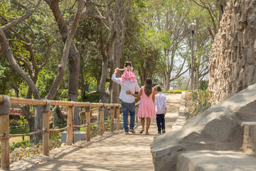 Family members walking together holding hands in a sunny day in a park in Lima Peru