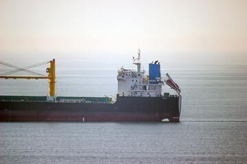 Back of a large ship with yellow cranes at sea on a white background