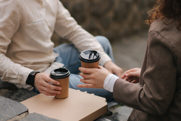Smiling love couple sitting on the stairs outdoor and hold cup of coffee. Middle selection