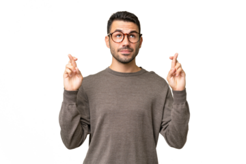 Young handsome caucasian man over isolated background with fingers crossing and wishing the best