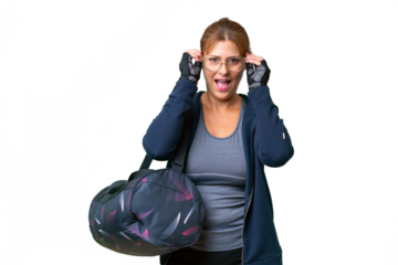 Middle-aged sport woman with sport bag over isolated background with glasses and surprised